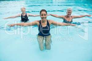 Female trainer with senior women exercising in swimming pool