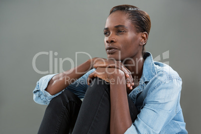 Androgynous man in denim shirt posing against grey background