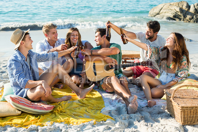 Friends having drinks while sitting on shore