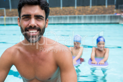 Smiling coach sitting near poolside