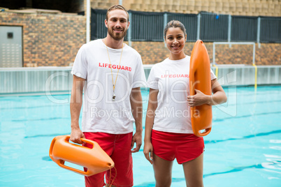 Two lifeguards standing with rescue buoy at poolside