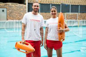 Two lifeguards standing with rescue buoy at poolside