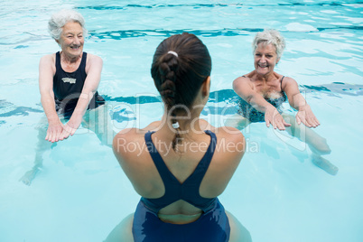 Female trainer with senior women exercising in swimming pool