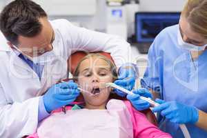 Dentist and nurse examining a young patient with tools