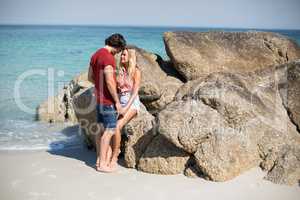 Romantic young couple by rocks at beach