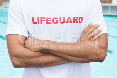 Mid section of lifeguard standing with arms crossed