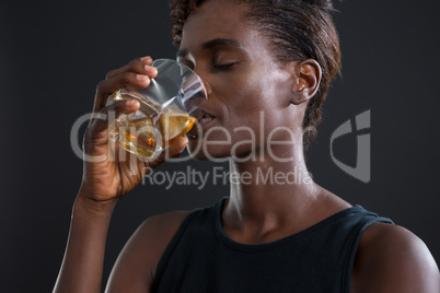Androgynous man drinking whiskey from glass