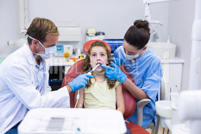 Dentists examining a young patient with tools