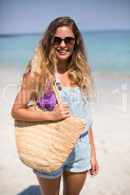 Young woman standing at beach on sunny day