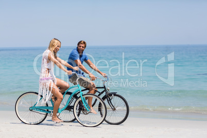 Happy couple riding bicycles on shore