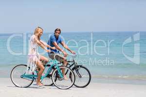 Happy couple riding bicycles on shore