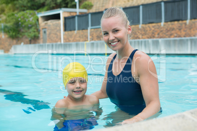 Portrait of female instructor and young boy standing in pool