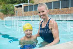 Portrait of female instructor and young boy standing in pool