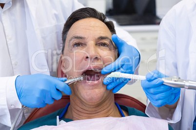 Dentist examining a male patient with tools