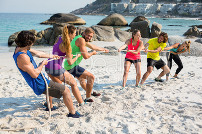 Friends playing tug of war on shore at beach