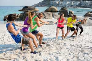Friends playing tug of war on shore at beach