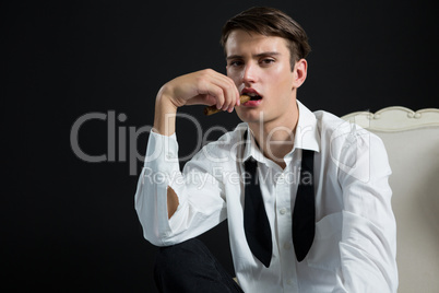 Androgynous man posing with cigar in his mouth