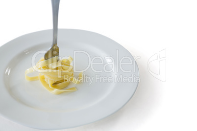 Spaghetti rolled up in fork with plate on white background