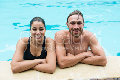 Smiling couple leaning on poolside