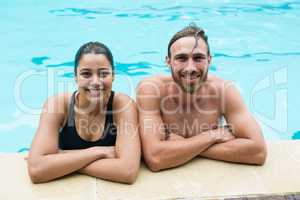 Smiling couple leaning on poolside