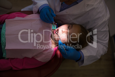 Dentist examining a young patient with tools