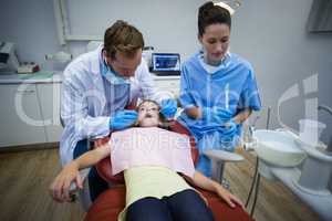 Dentists examining a young patient with tools
