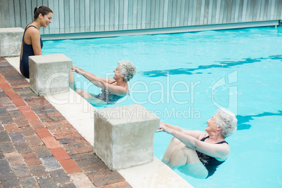 Trainer interacting with senior women at poolside