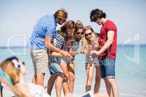 Friends gesturing while looking in mobile phone at beach