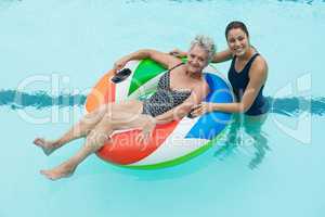 Female coach and senior woman smiling in swimming pool