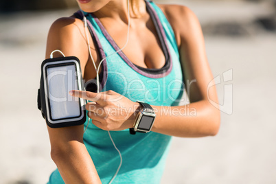 Midsection of woman using smartphone on armband
