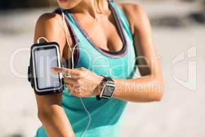 Midsection of woman using smartphone on armband