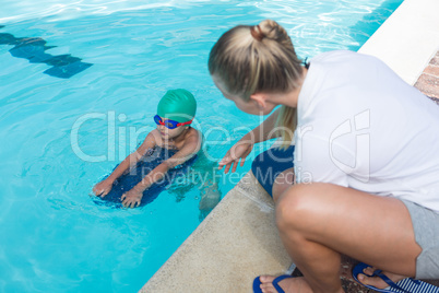 Female trainer training a boy for swimming