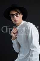 Androgynous man in hat posing with hand on collar