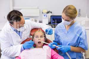 Dentist and nurse examining a young patient with tools
