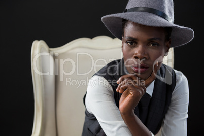 Androgynous man sitting on a chair with hand on chin