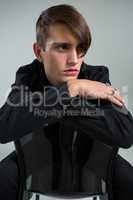 Thoughtful androgynous man sitting on chair