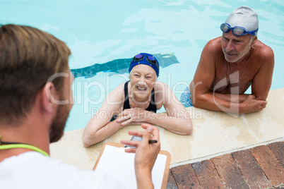 Swim coach interacting with senior couple