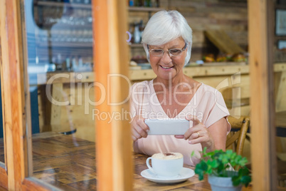 Senior woman photographing a coffee cup