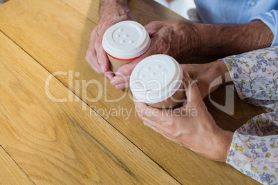 Senior couple holding disposable coffee cup