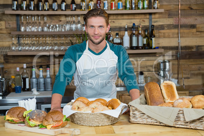 Smiling waiter standing behind the counter in cafe
