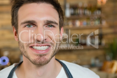 Smiling waiter standing behind the counter