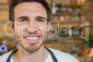Smiling waiter standing behind the counter