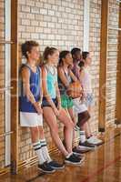 High school kids leaning against the wall in basketball court