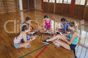 High school team using mobile phone while sitting in the basketball court