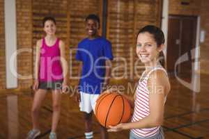 Portrait of smiling high school kids standing with basketball