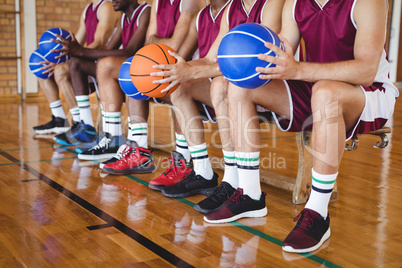 Basketball players sitting on bench with basketball