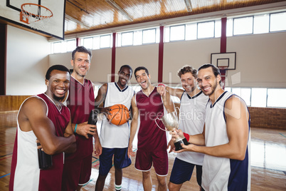 Smiling basketball players standing with throphy in the court