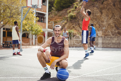 Basketball player with basketball sitting in basketball court