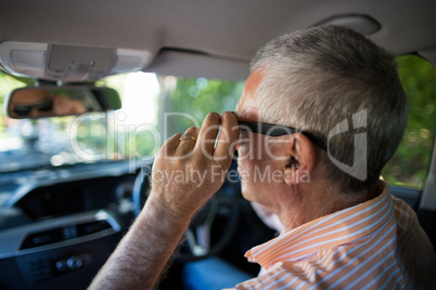 Senior man adjusting sunglasses in car