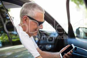 Smiling senior man using smart phone in car